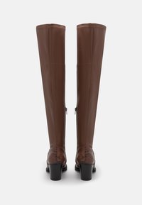 Botas de cuero marrón hasta la rodilla con un acabado suave, acentos en estampado de serpiente marrón texturizado en el tacón, detalle de cremallera lateral y tacones cuadrados.