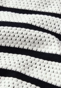 Gestrickter Stoff mit einem Netzmuster, das abwechselnd weiße und marineblaue Streifen zeigt. Das Material hat eine weiche, atmungsaktive Textur mit einer offenen Webart.