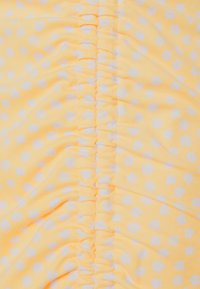 Geel stof met een klein wit bloemenpatroon en een centraal geplooide naadtoevoeging.