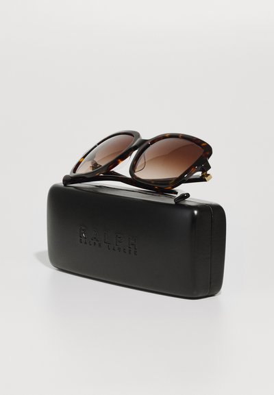 Schildpatt-Sonnenbrille mit braunen Verlaufslinsen, die auf einem schlichten schwarzen Etui liegen, das mit "RALPH" in Großbuchstaben geprägt ist.