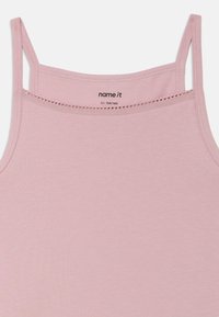 Lyserosa singlet i myk bomull, med tynne stropper og dekorativ kant langs halslinningen. Merke: "name it", størrelse EU 134/140.