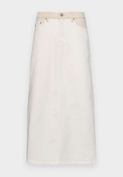 Fehér farmer szoknya magas derékkal, elülső zsebekkel és egyenes szabással. Kontrasztos varrással és gombos, cipzáras záródással rendelkezik.