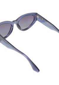 Ochelari de soare cu rame forme de ochi de pisică, de culoare mov, cu un finisaj lucios și lentile gradient. Prezintă brațe subțiri și îngustate cu detalii de branding pe partea interioară.