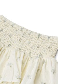 Gonna gialla chiara a balze con stampa floreale, dotata di vita smock e tessuto testurizzato. Visibili accenti di piccoli motivi a pois.