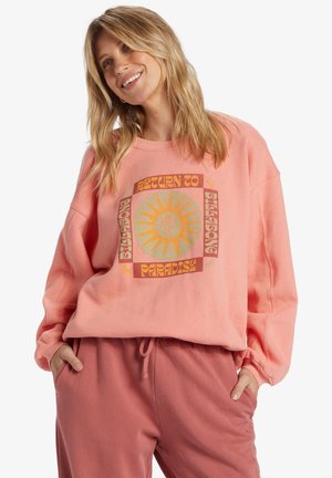 Perzikkleurige sweatshirt met een grote graphic waarop "Return to Paradise" staat, met zon- en palmmotieven. Zachte textuur en ontspannen pasvorm.
