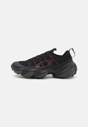 Black athletic shoes with a textured mesh upper, contrasting red accents, and a chunky rubber sole featuring rounded grips.