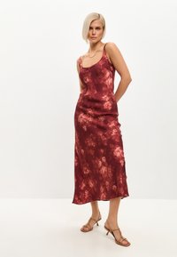 Rochie midi din satin de culoare maronie, cu un model floral, având bretele subțiri și o croială relaxată, asortată cu sandale cu curea de culoare marron deschis.