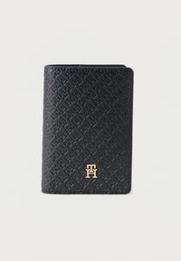 Μαύρο πορτοφόλι με υφή από ανάγλυφο δέρμα, με έμφαση σε χρυσό λογότυπο στο μπροστινό μέρος. Συμπαγής σχεδιασμός με ορθογώνιο σχήμα.