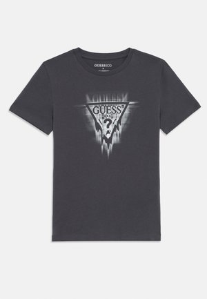 Tmavě šedé bavlněné tričko s trojúhelníkovou černobílou grafikou a textem "GUESS?" a abstraktními akcenty. Krátké rukávy a kulatý výstřih.
