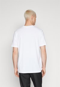 White cotton t-shirt with short sleeves and a crew neck. Simple design, smooth texture, no visible patterns or embellishments.