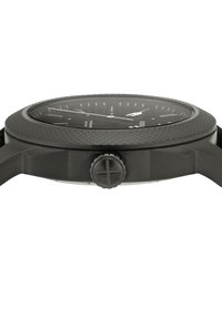 Montre noire avec une lunette texturée et un grand cadran. Dispose d'un bracelet lisse et d'une couronne proéminente. Un verre clair recouvre le cadran avec des marquages blancs.