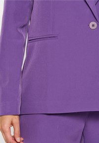 Lila skräddarsydd blazer med en slät struktur, enkel knappstängning och en framficka. Har långa ärmar och en strukturerad design.