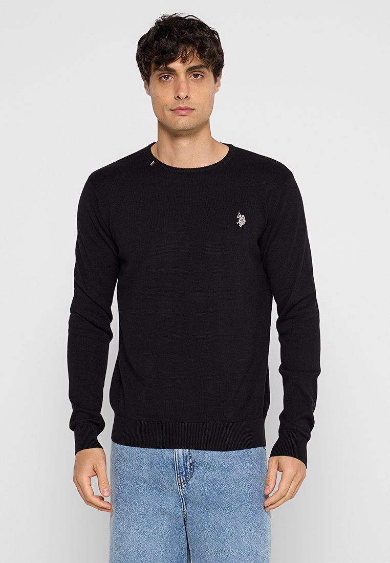 Schwarzer Strickpullover mit Rundhalsausschnitt, gerippten Bündchen und Saum. Mit einem kleinen gestickten Logo auf der Brust und einer dezenten Detailierung am Kragen.