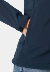 Marineblaues Jacket mit einem schlanken Design, verstellbarem Ärmelabschluss mit Klettverschluss und Seitentasche mit Kordelzug für eine angepasste Passform. Texturierter Stoff.