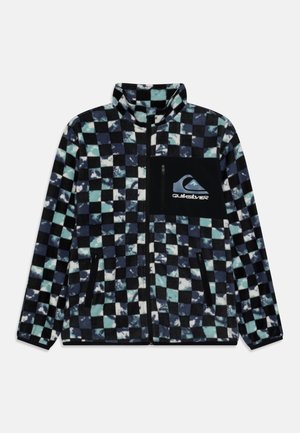 Veste polaire à motif à carreaux noir, bleu et blanc, poche poitrine zippée noire avec logo et deux poches latérales zippées.