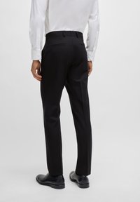 Svarte skræddersydde bukser med en glatt tekstur, slim fit og mid-rise livlinje, kombinert med en hvit langermet skjorte og svarte sko.