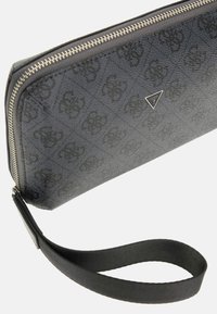Portefeuille zippé noir en matériau texturé, présentant un motif de logo subtil et une bandoulière pour un transport facile.