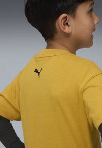 Dzeltena īsām piedurknēm T-krekls, izgatavots no kokvilnas, ar melnu Puma logo izšuvumu aizmugurē. Maiga tekstūra un brīvs piegriezums.