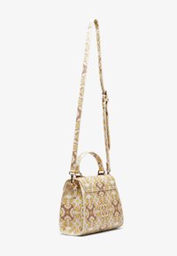 Kuvioitu käsilaukku valkoisena, keltaisena ja ruskeana; jämäkkä muoto, jossa yläkahva, irrotettava hihna ja kullanväriset metalliosat.