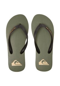 Des tongs en caoutchouc vert avec des brides noires. Semelle texturée, logo en or sur le côté, et un design minimaliste.