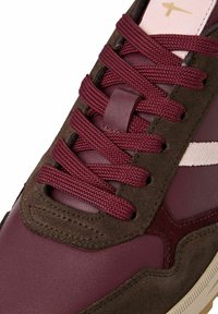 Maroon sneaker featuring a combination of smooth leather and suede, with textured laces and a contrasting white stripe on the side.