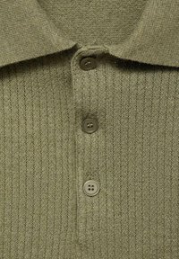 Polo shirt en tricot vert olive avec une texture côtelée, doté d'un col évasé et de quatre boutons assortis sur le devant.