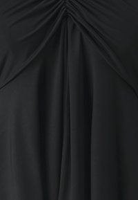 Zwarte jurk met geraffineerde stof bij de halslijn en vloeiende plooien. Gladde textuur met een gelijkmatige kleur overal.