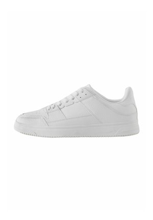Lavskoet helt hvid sneaker med snøredesign, teksturerede læderpaneler og en flad gummisål set fra siden.