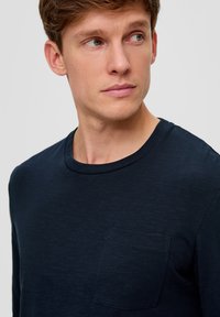 Granatowa longsleeve koszula z miękkiej, teksturowanej tkaniny, z okrągłym dekoltem i kieszonką na piersi.