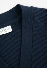 Granatowy kardigan z prążkowanego dzianiny z dekoltem w kształcie litery V i delikatną teksturą. Widoczna metka z nazwą marki i szczegółami dotyczącymi rozmiaru.