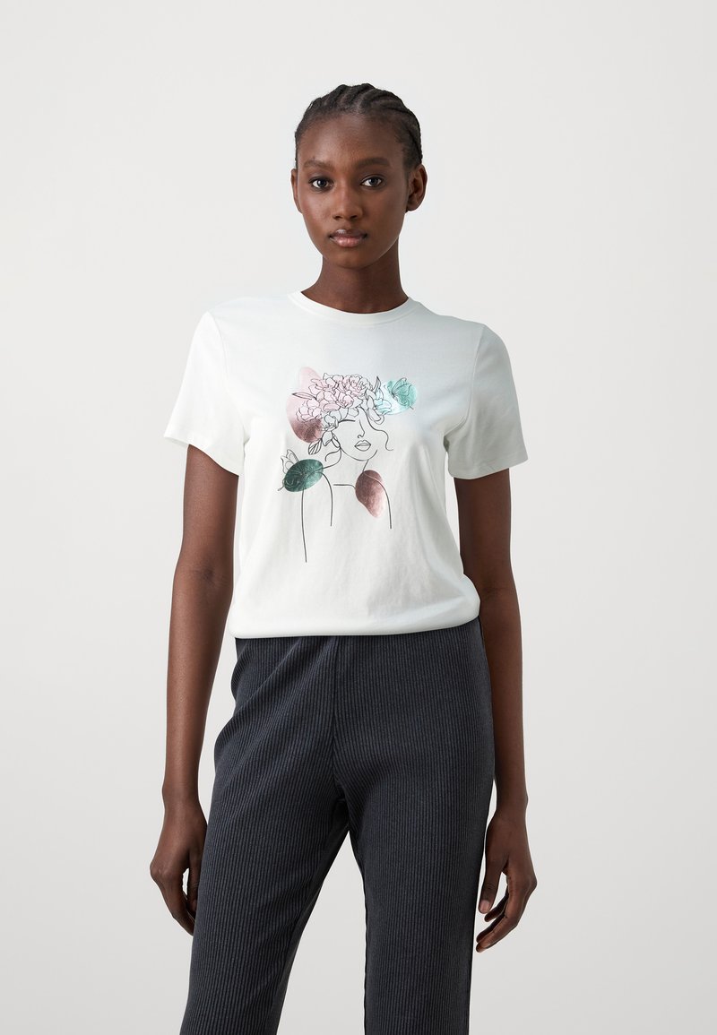 White short-sleeve T-shirt featuring an outlined face design with floral accents in pink and green, paired with dark textured pants.