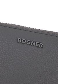 Grijze gestructureerde leren portemonnee met een opvallend zwart "BOGNER" logo. De rits is zichtbaar langs de bovenrand en toont nauwkeurige stiksels.