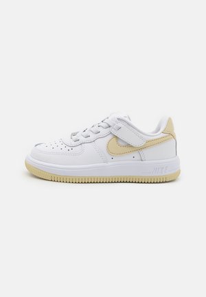 White sneaker with gold accents, featuring a smooth leather upper, perforated toe box, lace closure, and textured rubber outsole.