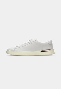 Fehér bőr sneaker lekerekített orral, lapos talppal és diszkrét márkajelzéssel. Texturált sarokkal rendelkezik, és barna-fekete csíkos díszítéssel van ellátva.