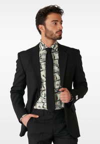 Black tailored suit jacket and pants with a graphic shirt featuring currency patterns. Necktie matches suit, creating a cohesive look.