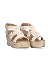 Sandalias de cuña con tiras trenzadas en crema, hebilla en el tobillo y una plataforma de cuerda beige texturizada. Plantilla marrón suave.