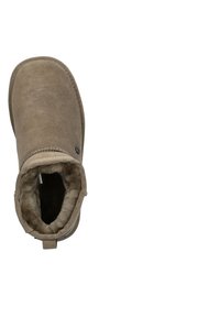 Beige enkellaars gemaakt van suède met een zachte, met bont gevoerde binnenkant, voorzien van een achterste trekhaak en gestikte details langs de randen.