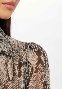 Doorzichtige blouse met een slangenprint in beige en bruine tinten, met een kraag en geplooide details op de schoudernaad.