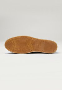 Semelle de chaussure en caoutchouc avec un motif en nid d'abeille, de couleur marron, et surface texturée. Taille 42 estampillée sur le côté, design plat avec un bout arrondi.