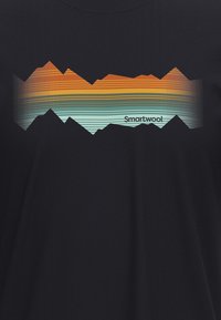 Czarny T-shirt z graficznym wzorem przedstawiającym ząbkowane kształty gór w pomarańczowych, turkusowych i jasnoniebieskich paskach, z napisem "Smartwool" na dole.