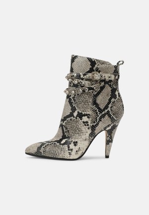 Bottes cheville en peau de serpent avec un bout pointu et un talon haut, ornées de deux lanières décoratives avec des strass traversant la cheville.