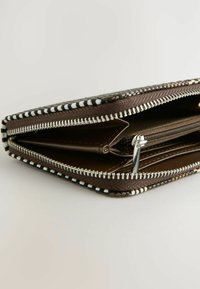 Portafoglio marrone con cerniera, rivestito in tessuto decorato, caratterizzato da cuciture bianche a contrasto e molteplici scomparti per l'organizzazione.
