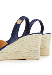 Sandalias de cuña de ante azul marino con tacones de yute trenzado, que cuentan con dos tiras tipo slingback y un acento en color tostado con el logo en una de las tiras.