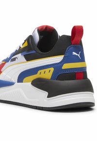 Baskets avec une tige synthétique aux accents noirs, bleus, rouges et jaunes ; col rembourré et semelle blanche avec des détails texturés.