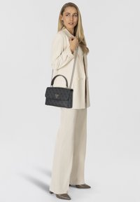 Černá kožená kabelka s texturou vzoru, stříbrným řetízkovým popruhem a horním držadlem. Na přední straně je trojúhelníková logová značka.