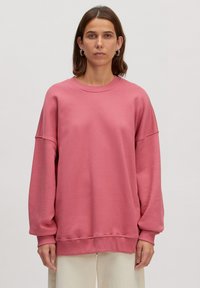 Roze, oversized sweatshirt met lange mouwen en een ronde halslijn. Gemaakt van een zachte, gestructureerde stof. Heeft ribgebreide manchetten en een zoom.