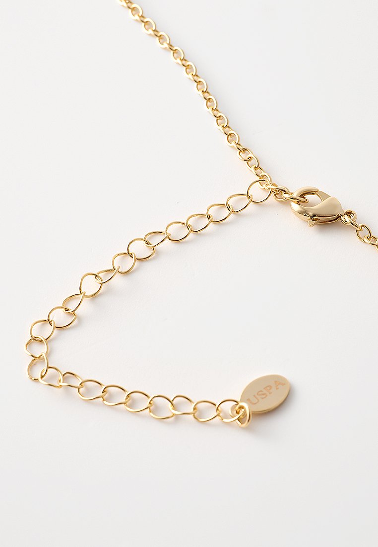 Collar de cadena de oro con extensión de eslabones ovalados, cierre de langosta y pequeña etiqueta redonda grabada con "USPA" sobre un fondo blanco.