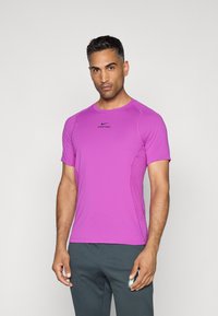 T-shirt de sport violet à manches courtes fabriqué en tissu léger, avec un col rond et le logo Nike Pro à l'avant.