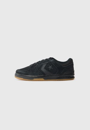 Sort lavtop Converse-sneaker med stjerne-logo på siden, sort sål og gummifarvet ydersål, vist fra ydersiden på en lys baggrund.