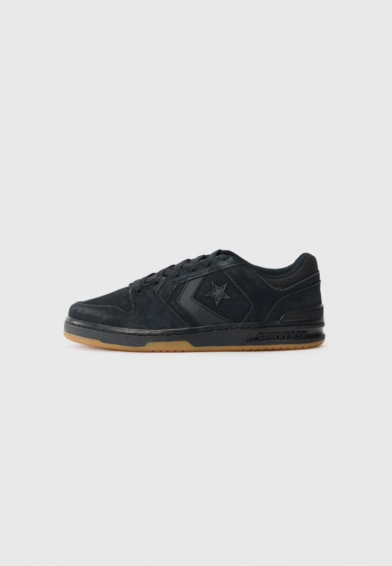 Baskets basses noires Converse avec logo étoile sur le côté, semelle noire et semelle extérieure couleur gomme, vues de côté extérieur sur fond clair.